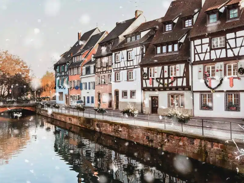 Colmar, France in winter snowstorm. Historical buildings along canal in the city center in snowy weather. 