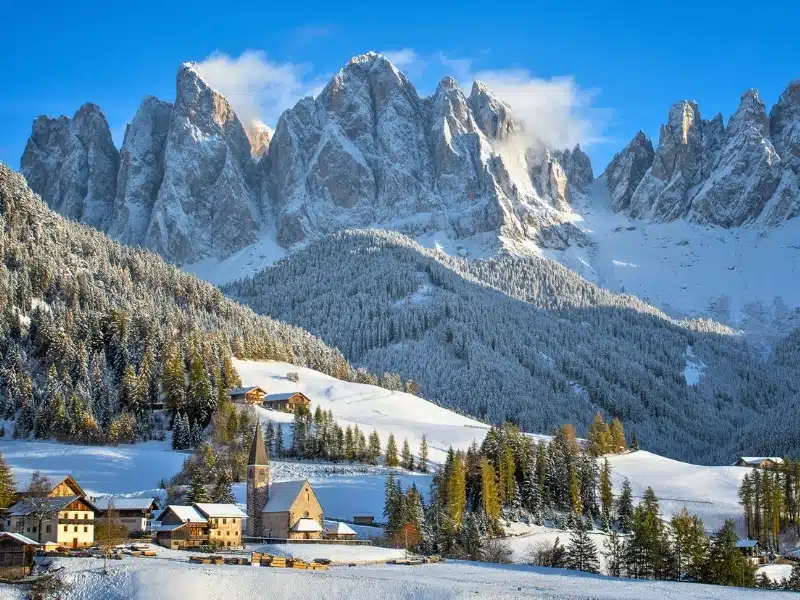The small village of St. Magdalena or Santa Maddalena with its church covered in snow and with the Odle or Geisler Dolomites mountains in the Val di Funes Valley in South Tyrol in Italy in winter.