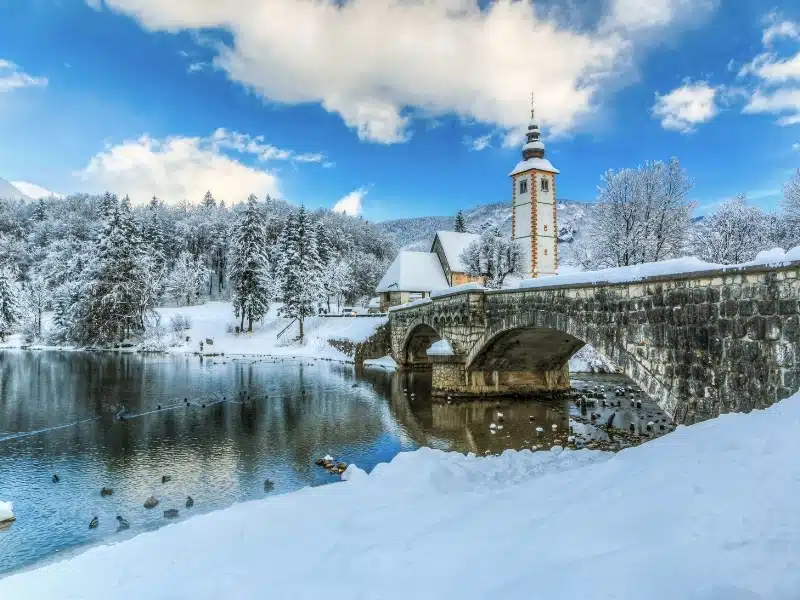 Church of Sv. John the Baptist and a bridge by the Bohinj lake  in winter, Slovenia 