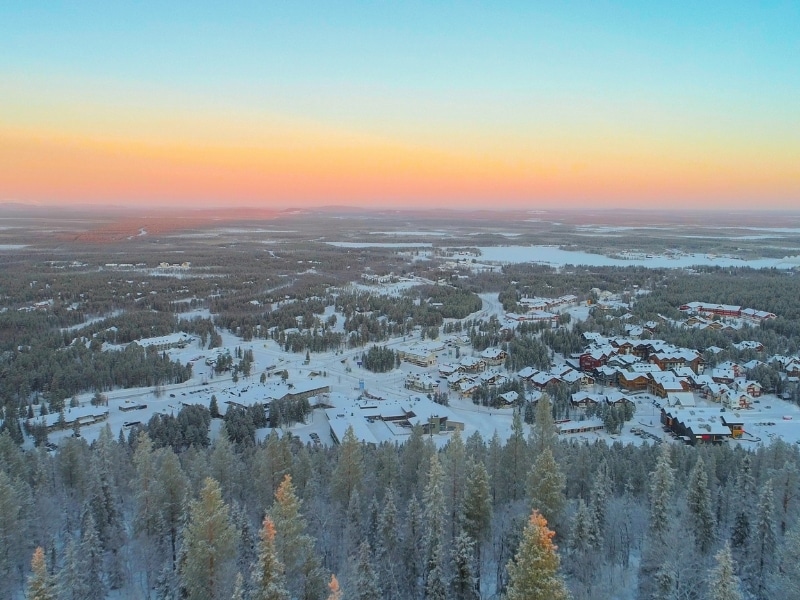 Flying over frozen pine trees, revealing Levi ski resort Finland