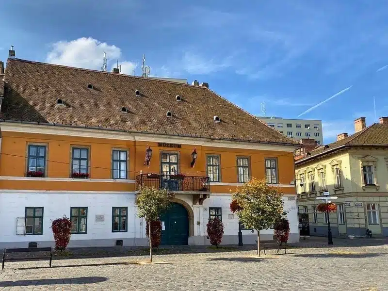 Cobbled square with orange and white building and trees