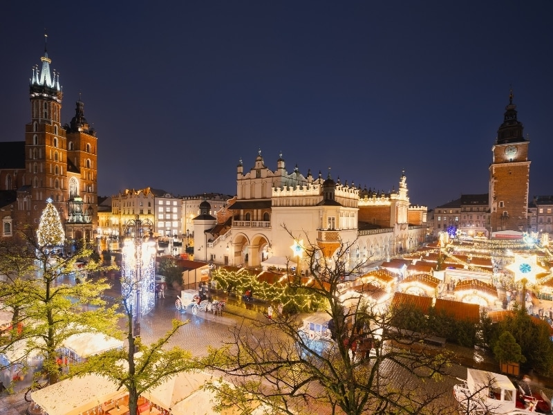 View of the Krakow Christmas Market and the historic Old Town Square, beautifully illuminated with festive lights and vibrant holiday atmosphere