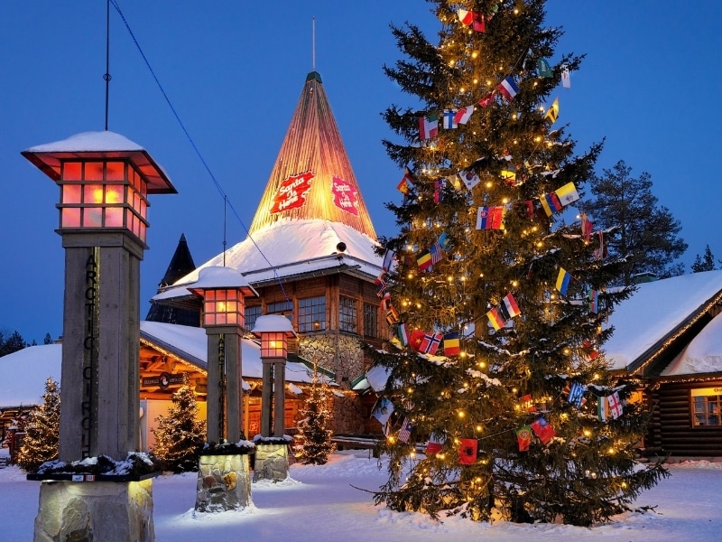 Santa Claus office in Santa Village in Rovaniemi with Christmas trees at night illuminated with light, Lapland, Finland, on Arctic Circle in winter.