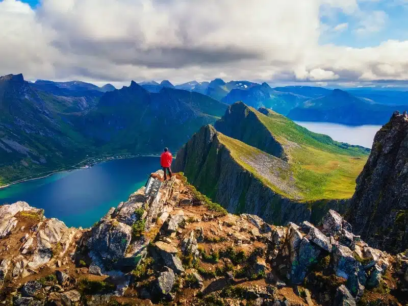 tanding in a rocky summit with a mountain range view in the distance