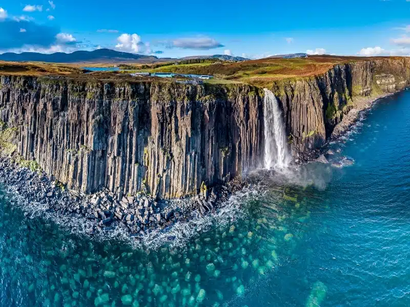 Aerial view of a dramatic coastline and cliffswith a waterfall cascading into the sea