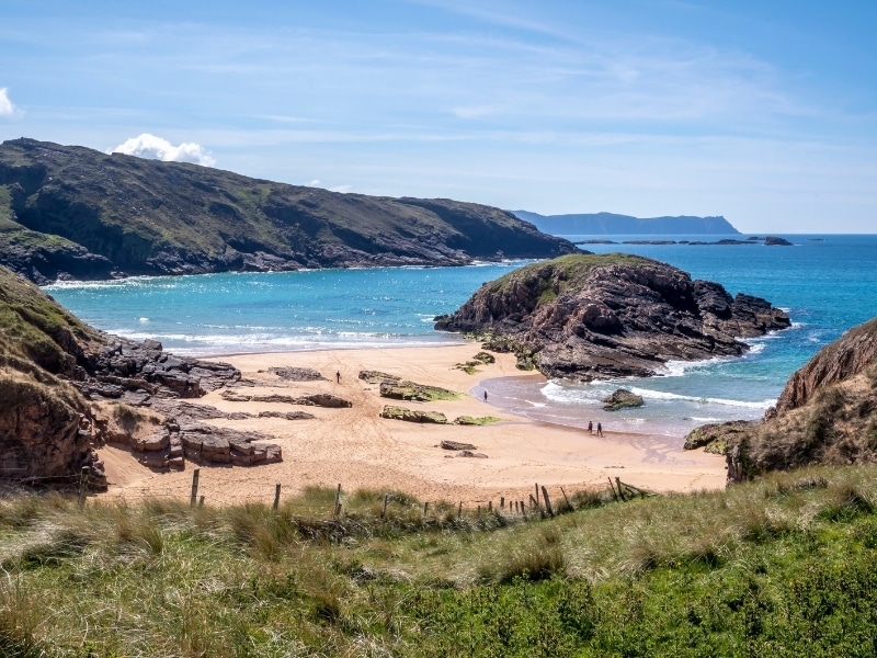 Sandy back with a grassy cliff and  rocky peninsula