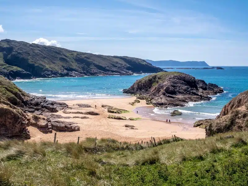 Sandy back with a grassy cliff and  rocky peninsula