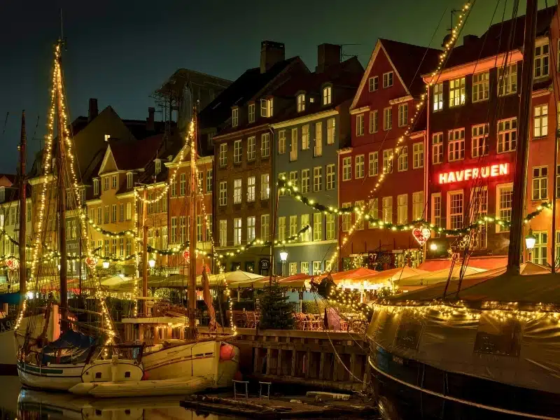 Street of Danish town houses along a dock full of boats and Christmas lights