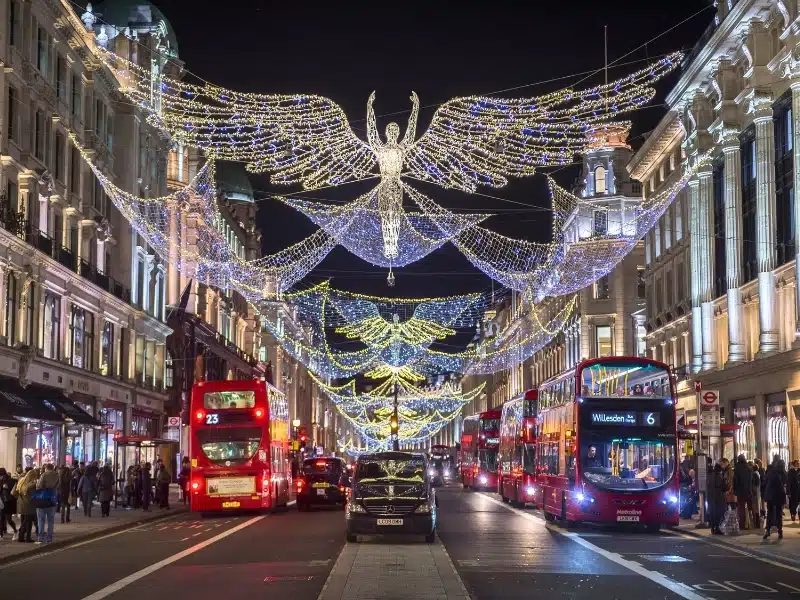 Traditional black taxi waits for customers under twinkling Christmas angels lighting up the upscale shopping district of Regent Street.