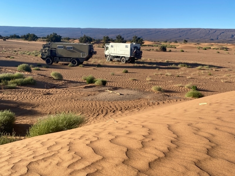 Two overland trucks parked in a dessert landscape