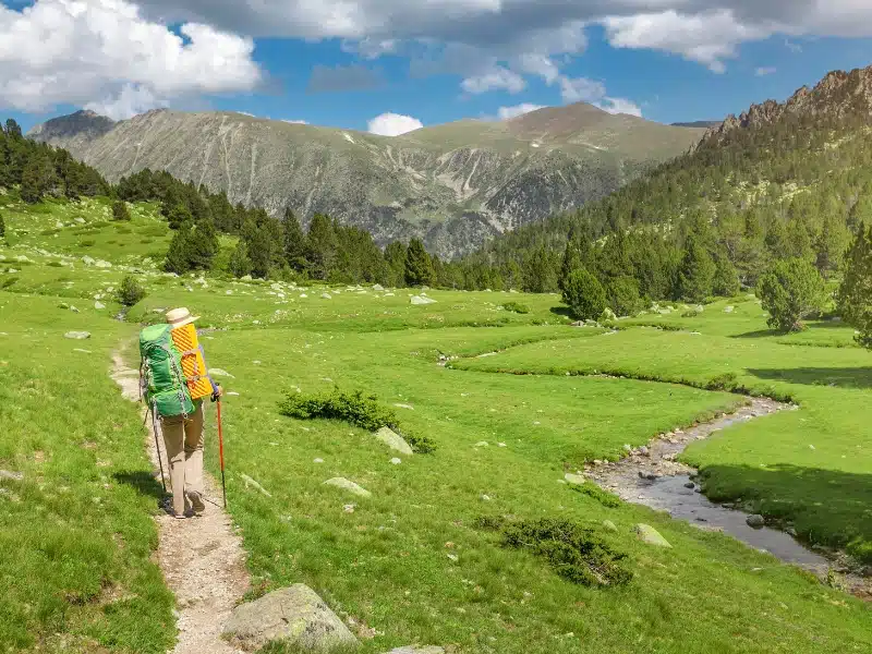 A hiker woman travels along small river during GR11 Hike in Pyrenees mountains