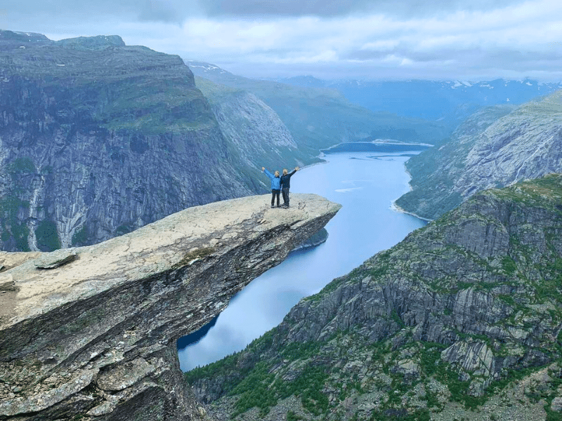 Phil and Izzy standing on the Troll's Tongue on a cloudy day