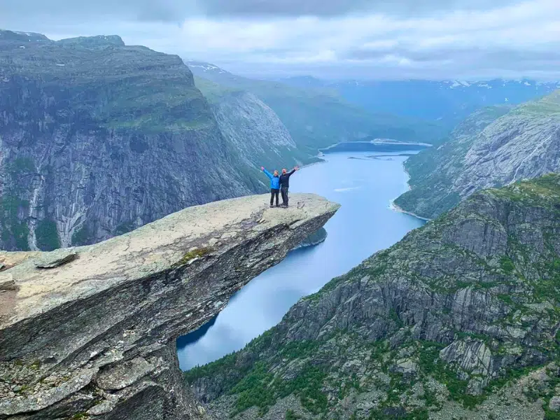 Phil and Izzy standing on the Troll's Tongue on a cloudy day