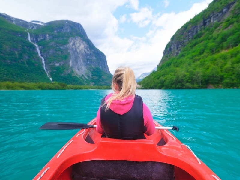 A girl sailing a canoe on a Norwegian fjord in Scandinavia