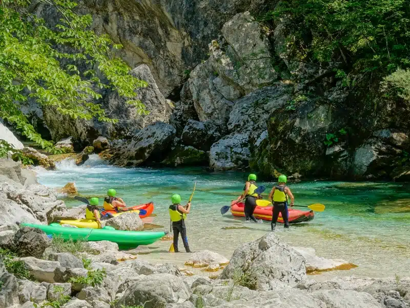 A group of active tourists prepare their canoes for a rafting trip down the gorgeous Soca river.