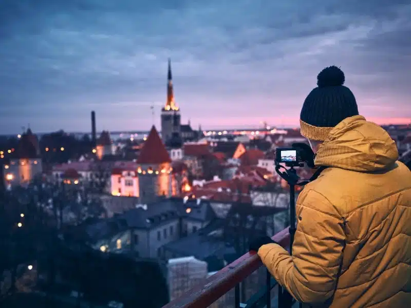Photographer with camera on tripod photographing old town of Tallinn at sunrise. 