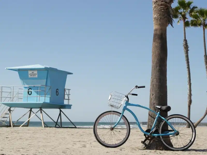 Blue bicycle, cruiser bike by sandy ocean beach, pacific coast near Oceanside pier, California USA.