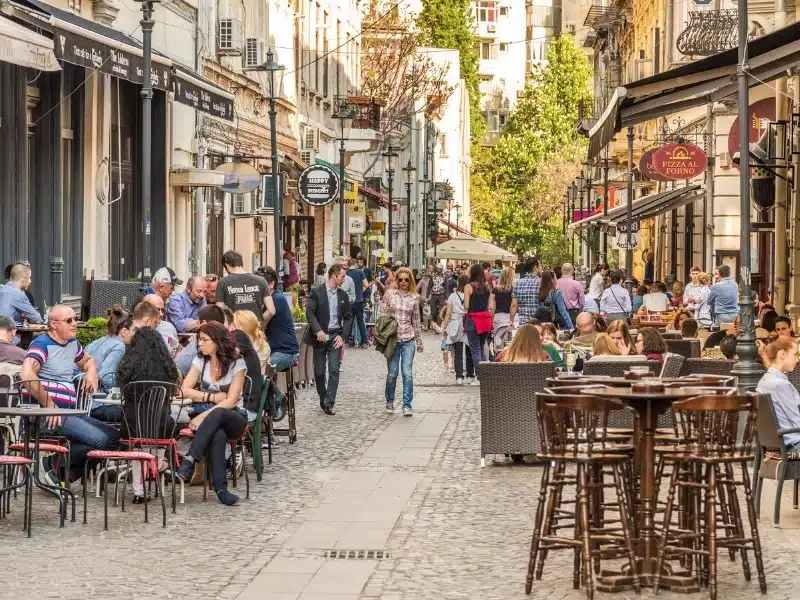 Tourists Visiting And Having Lunch At Outdoor Restaurant Cafe Downtown Lipscani Street, one of the busiest streets of central Bucharest.