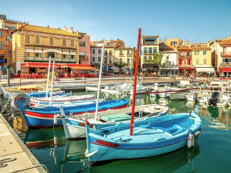 Colourful boats in a harbour surrounded by pastel coloured houses
