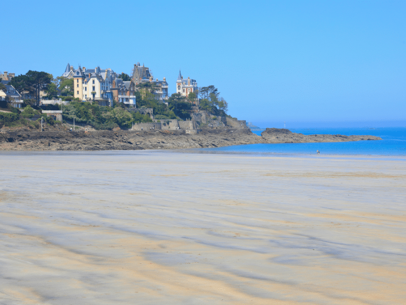 Expansive sandy beach with view of cliff top houses and the ocean