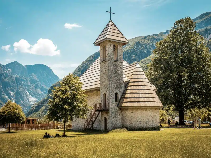 Traditional wooden roofed Albanian church surrounded by mountains