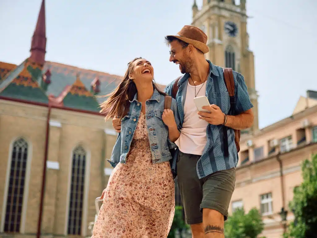 Happy couple of tourists laughing and having fun while walking in the city.