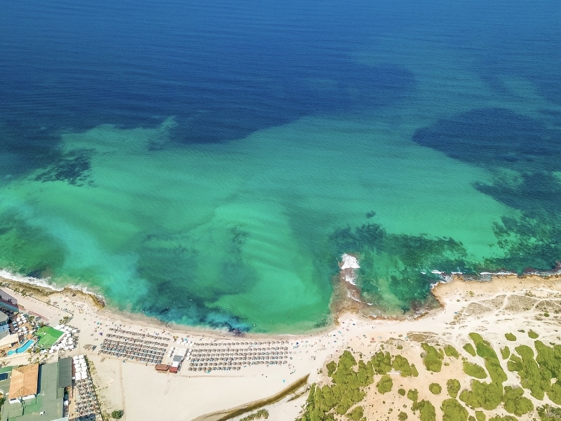 Natural coastal and beach landscape drone panorama with turquoise water waves mountains and forest from Alcúdia bay and Playa del Muro in Can Picafort on Balearic island Mallorca in Spain.