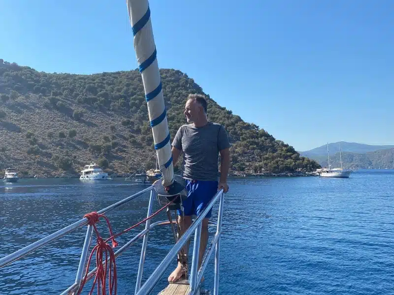 Man on the bow of a sailing boat in a blue sea