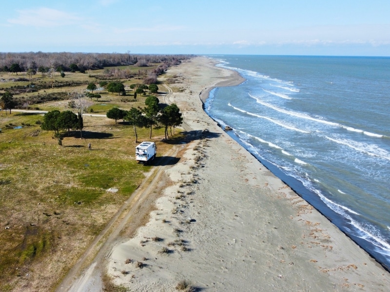 motorhome parked bwteeen grassy fields, the beach and sea