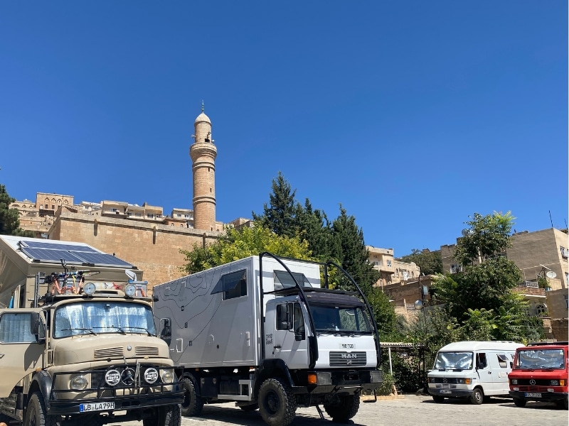 campervans and motorhomes parked in front of a walled city and minaret