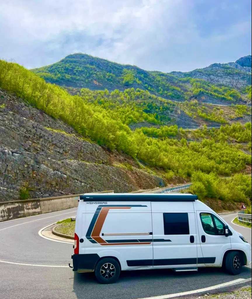White campervan on a switchback bend of a tarmac road