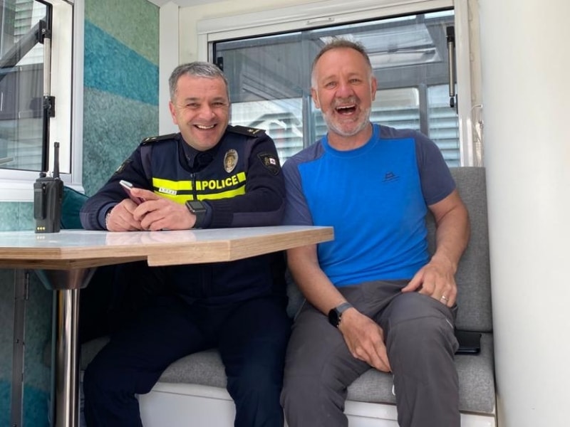 Two men ina. truck, one wearing a Police uniform