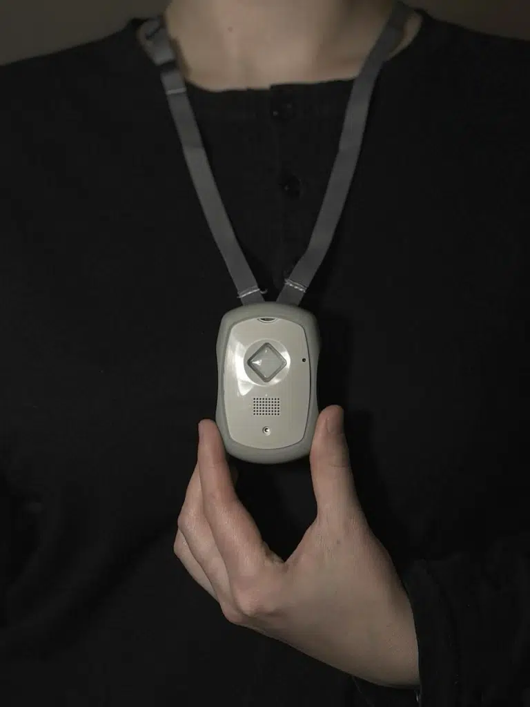 A person wearing a medical alert pendant on a lanyard around their neck for hands-free safety