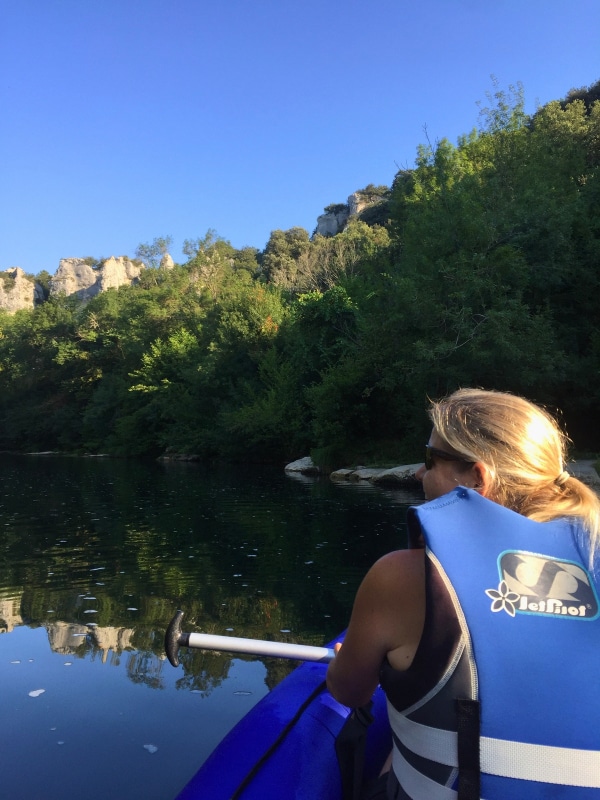 Woman in blue lifejacket kayaking ona. still river