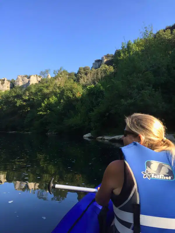 Woman in blue lifejacket kayaking ona. still river