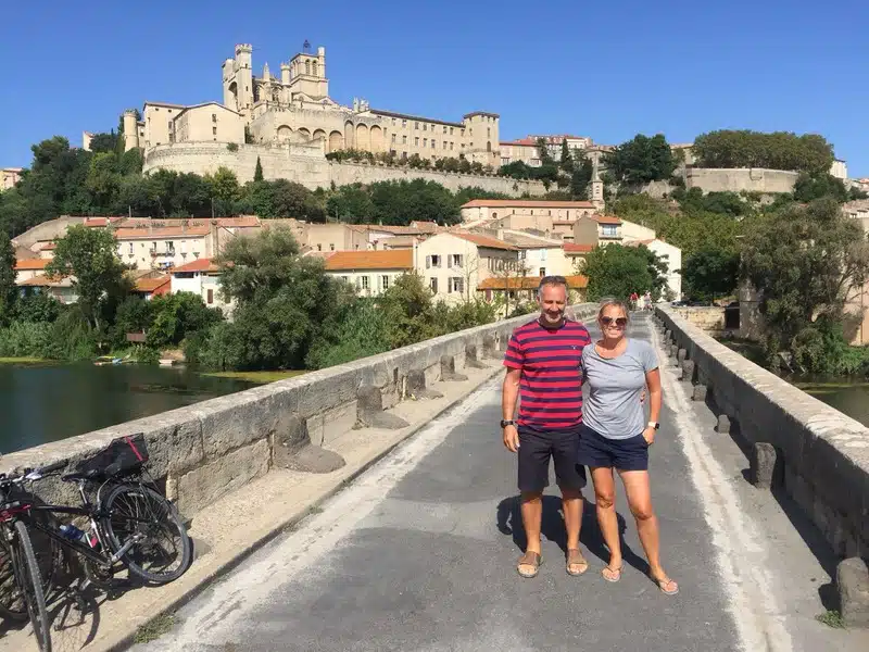 Couple on the old bridge over the Orb river with the Cathedral of Saint Nazaire in Beziers
