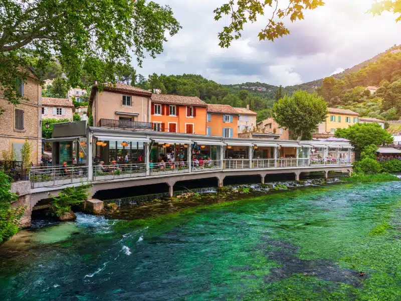 Fontaine de Vaucluse village with charming riverside in a picturesque town with colorful buildings during a peaceful afternoon. France, Provence, Vaucluse, Pays des Sorgues, Fontaine de Vaucluse.