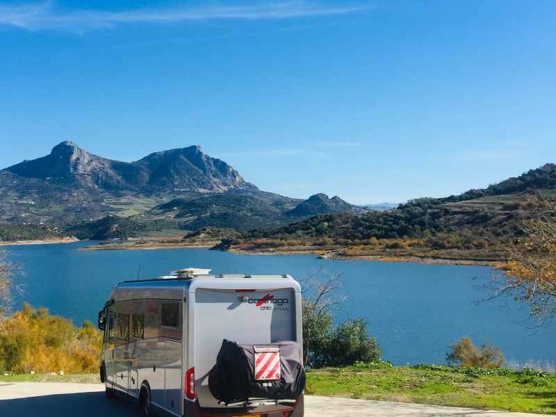 silver motorhome overlooking a lake to mountains
