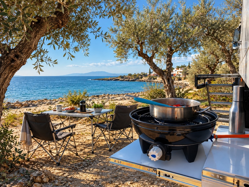cooking outside an overland truck with table and chairs by the sea